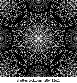Seamless vector ethnic ornament. Openwork white pattern of mandalas on a black background.