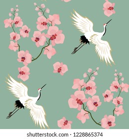 Seamless vector illustration with birds cranes and orchids on a green background. For decoration of textiles, packaging, wallpaper.