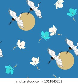 Seamless vector illustration with birds cranes and hibiscus flowers on a blue background. For decorating textiles, packaging, web design.