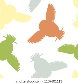 Seamless vector pattern with brown, yellow and green owls. Repetitive background with vector flat multicolored birds. Owls in the repetitive seamless vector pattern.