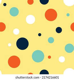 Seamless vector pattern with colourful dots on yellow background. Simple fun children wallpaper design. Decorative happy polka dots fashion textile.