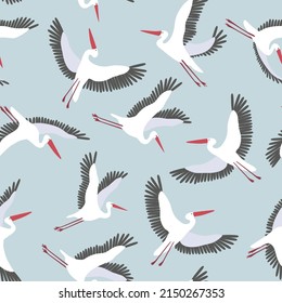 Seamless vector pattern with flying white storks. Graphic print with birds on a blue background.