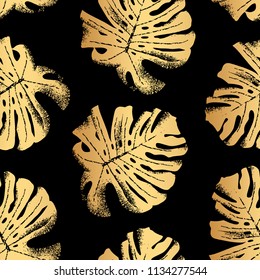 Seamless vector pattern with golden monstera leaves isolated on black background.