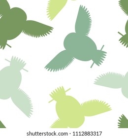 Seamless vector pattern with green owls. Repetitive background with vector flat multicolored birds. Owls in the repetitive seamless vector pattern.