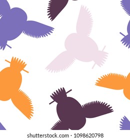 Seamless vector pattern with orange, purple, pink owls. Repetitive background with vector flat multicolored birds. Owls in the repetitive seamless vector pattern.