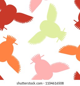 Seamless vector pattern with orange, red, pink and green owls. Repetitive background with vector flat multicolored birds. Owls in the repetitive seamless vector pattern.