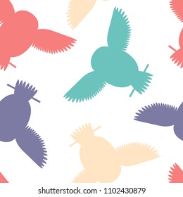 Seamless vector pattern with orange, teal, red, purple owls. Repetitive background with vector flat multicolored birds. Owls in the repetitive seamless vector pattern.