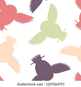 Seamless vector pattern with red, purple and green owls. Repetitive background with vector flat multicolored birds. Owls in the repetitive seamless vector pattern.
