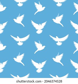 Seamless vector pattern with white pigeons on a blue background. Doves fly in the blue sky. Vector illustration.