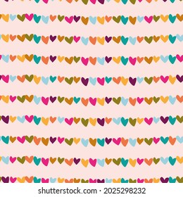 seamless vector repeat pattern with colourful heart shapes arranged in rows on a light pink background