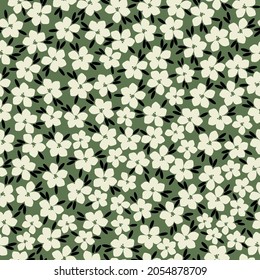 Seamless vintage pattern. cute white flowers and black leaves on a green background. vector texture. trend print for textiles, wallpaper and packaging.