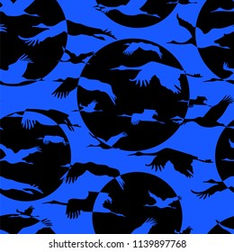 Seamless wallpaper with silhouette flying Japanese cranes on blue sky background. Monochrome blue black pattern