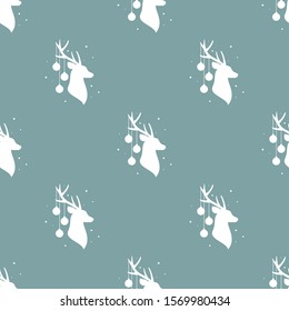 seamless winter pattern with white silhouette of deer head with antlers and christmas tree toy balls on horns. vector flat Christmas ornament on powder blue background