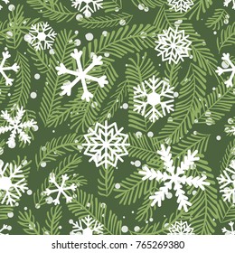 Seamless winter vector pattern with pine branches and white snowflakes on green background