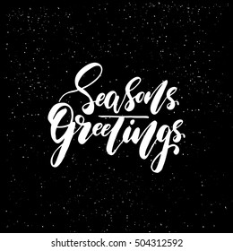 Seasons greetings - brush script calligraphic design for Xmas greetings cards, invitations. Handwritten calligraphy on black subtle ink spotted texture background.