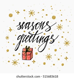 Season's Greetings card with gold glitter snowflake, stars and christmas present. Hand lettering calligraphic inscription by brush for Christmas, New Year greeting card template. Vector illustration