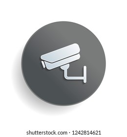 Security camera. Technology icon. White paper symbol on gray round button or badge with shadow