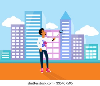 Selfie on smartphone using monopod. Young man taking own self portrait with mobile phone and stick on background with city town. Man standing on the street and photographed