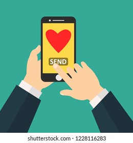 Sending love message concept. Hand holding phone with heart, send button on the screen. Finger touch screen. 