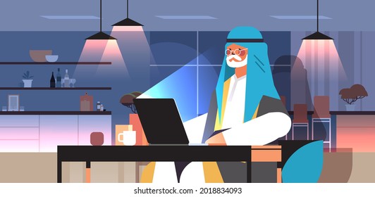 senior arab businessman freelancer working on laptop arabic man sitting at workplace in dark night home room