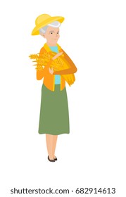 Senior caucasian female farmer holding hay in hands. Full length of happy female farmer with hay in hands. Farmer carrying hay. Vector flat design illustration isolated on white background.