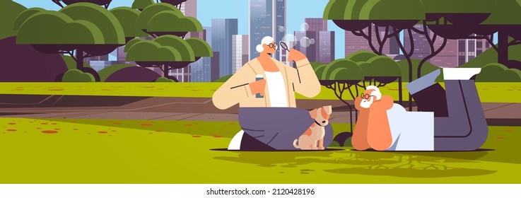 senior couple blowing bubbles and spending time with little dog in urban park relaxation retirement concept