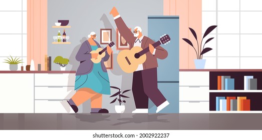 senior couple playing guitar grandparents having fun active old age concept home kitchen interior