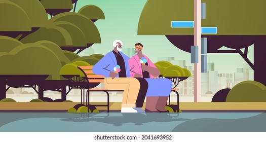 senior couple sitting on bench and eating ice cream happy african american grandparents spending time together in park