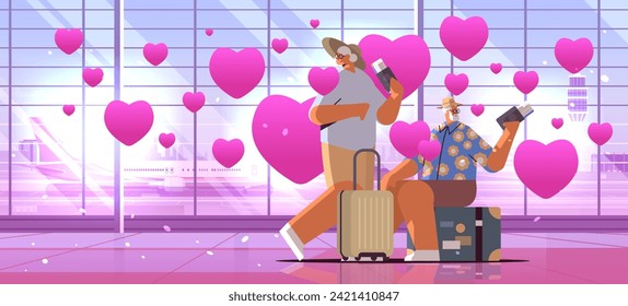 senior couple of tourists grandparents in love with luggage holding passports and tickets at airport with pink hearts valentines day celebration