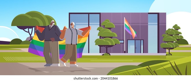 senior gay couple holding rainbow flag near new modular house transgender love LGBT community concept