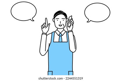 A senior man in an apron pointing while on the phone.