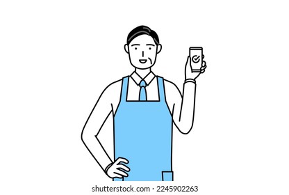 A senior man in an apron using a smartphone at work.
