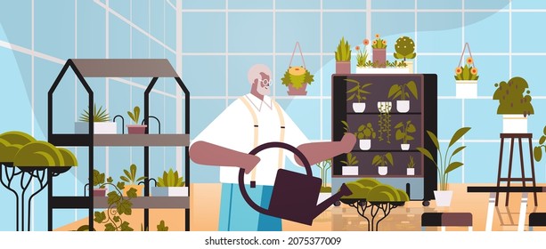 senior man gardener with watering can taking care of potted plants at home garden living room or office interior