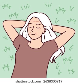 Senior old older elder Joyful white-haired woman. Senior woman with white hair lies on grass with closed eyes and hands behind head. Symbol of peaceful retirement, self-care, and emotional well-being