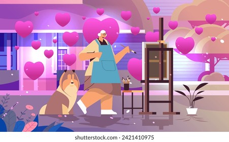 senior woman artist with dog painting picture on backyard with pink love hearts valentines day celebration concept horizontal