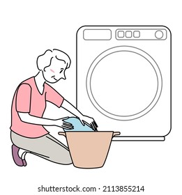 Senior woman doing laundry. Happy mature woman washing clothes. Housewife doing laundry at home. Elderly lady loading clothes into the washer. Mature woman putting laundry in basket in front of washer