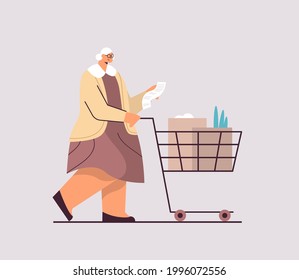 senior woman with full of products trolley cart checking shopping list in supermarket horizontal