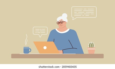 Senior woman studies and studies modern technologies using a laptop. A positive smiling grandmother sits at a computer, communicates on the Internet online and learns new things. An adult is working