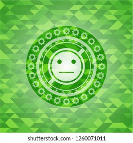serious face icon inside green emblem. Mosaic background