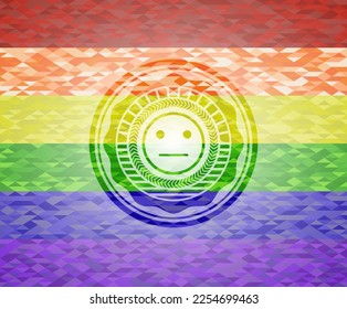 icono de cara seria sobre fondo de mosaico con los colores de la bandera LGBT. 
