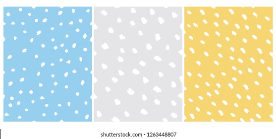 Set of 3 Cute Abstract Dots Vector Pattern. White Irregular Brush Dots on a Gray, Yellow and Blue Backgrounds. Lovely Pastel Color Delicate Layouts. Funny Infantile Style Design.