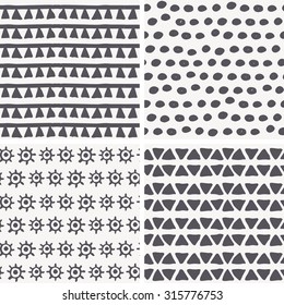 Set of 4 hand drawn geometric seamless patterns in primitive (tribal) style. Monochrome. Endless backdrop with triangles, dots, archaic symbols of the sun