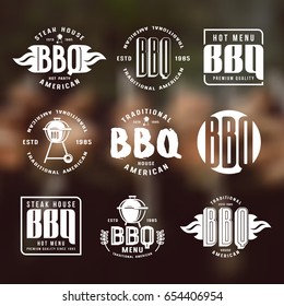 Set of barbecue labels and emblems. White print on blurred background