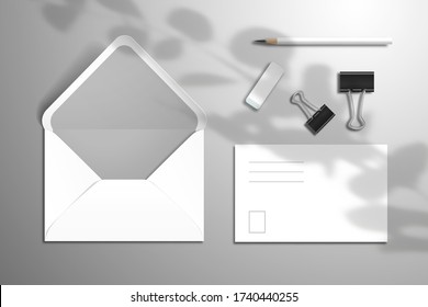 Set aus weißer leerer Postkarte, Umschlag, Bleistift, Radiergummi und Bindemittel. Mockup für Design mit Schatten aus der Eukalyptusbranche