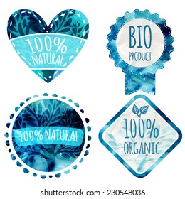 Set of blue vector eco badges with paper texture and leaves. Text on badges: 100% natural, organic, bio product. Shapes of heart, circle, award, lozenge.
