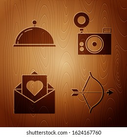 Set Bow and arrow, Covered with a tray of food, Envelope with Valentine heart and Photo camera on wooden background. Vector