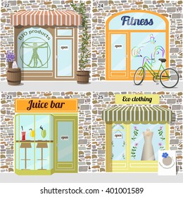 Set of buildings healty lifestyle set.Bio products shop. Eco clothing shop.  Dress in the window. Fresh juice bar building. Fitness center. Bike at the fore. Facade of stone.EPS10 