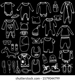 Set of children clothes in line, doodle style. Hygiene products for newborns, diapers, bottle, nipple. Hand drawn black outline. Vector illustration. Imitation of chalk drawing on black chalkboard.