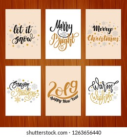 Set of christmas greeting cards with hand written lettering on wooden background.