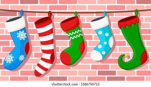 Set of Christmas socks hangs on a rope against a brick wall.